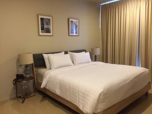 1 dormitorio con 1 cama grande con sábanas y almohadas blancas en Beach Front Condo, Baan Thew Talay, Perfect Choice for Family and Couple en Ban Bo Khaem