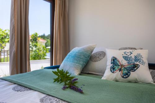Una cama con almohadas con cojines de mariposa. en VSG Resort, en Klimno