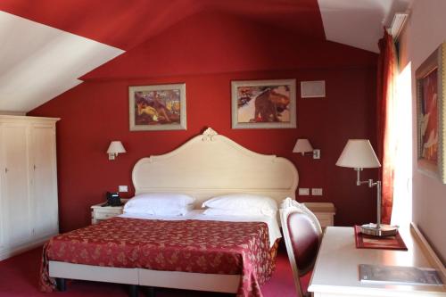 um quarto com uma parede vermelha e uma cama. em Hotel Capovilla em Pisogne