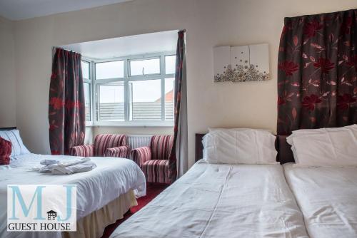a guest house bedroom with two beds and a chair at M and J Guest House in Cleethorpes