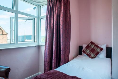 a bedroom with a bed and a window with curtains at M and J Guest House in Cleethorpes