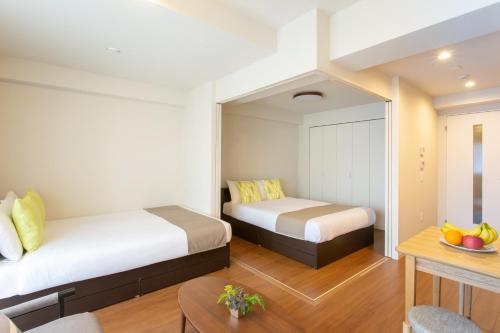 大阪的住宿－BON Condominium Umeda，酒店客房设有两张床和一张桌子。