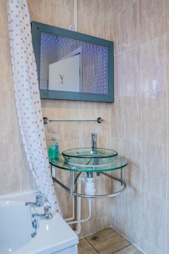 a bathroom with a glass sink and a mirror at M and J Guest House in Cleethorpes