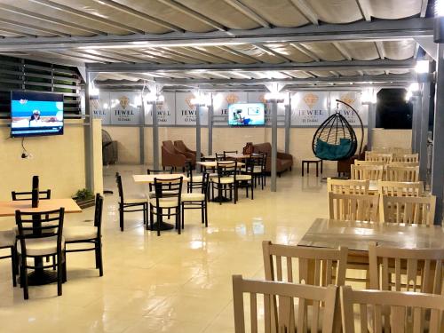 Jewel Dokki Hotel في القاهرة: غرفة طعام بها طاولات وكراسي وتلفزيون