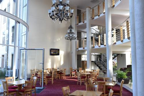 a restaurant with tables and chairs and a chandelier at Regal Inn PMBurg in Pietermaritzburg