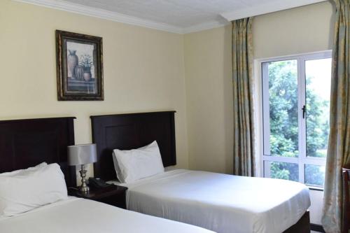pokój hotelowy z 2 łóżkami i oknem w obiekcie Regal Inn PMBurg w mieście Pietermaritzburg
