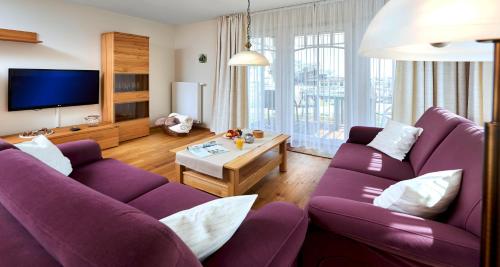 a living room with two purple couches and a tv at Haus EbenEzer in Büsum