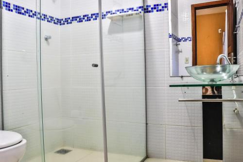 a bathroom with a glass shower and a sink at Pousada Das Araras in Itaúnas