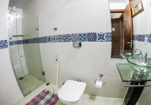 a bathroom with a shower and a toilet and a sink at Pousada Das Araras in Itaúnas