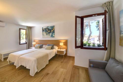 a bedroom with two beds and a window and a couch at Apartamento Ferrera Park 615 in Cala Ferrera