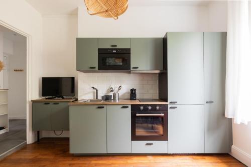 une cuisine avec des armoires blanches, un évier et un réfrigérateur dans l'établissement DIFY Gouraud - Lyon 8, à Lyon