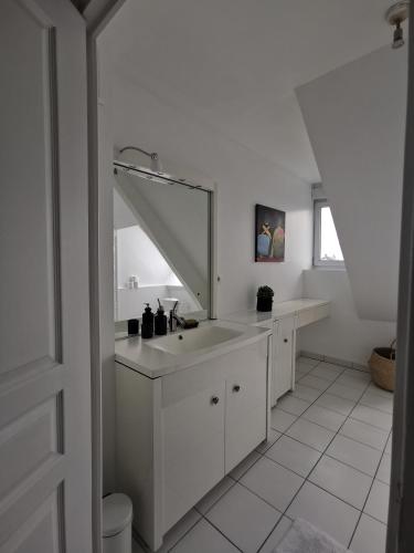 une salle de bain blanche avec un lavabo et un miroir dans l'établissement Suite de l'Etape - Vue cathédrale, à Reims