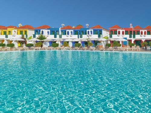 a pool of water in front of colorful buildings at Bungalows Vistaflor in Maspalomas