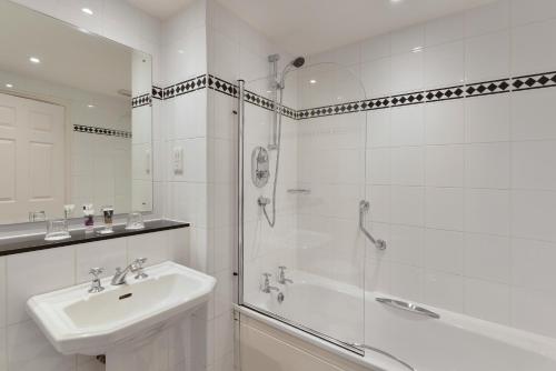 羅奇代爾的住宿－曼徹斯特諾頓格蘭治Spa美居酒店，带淋浴、盥洗盆和浴缸的浴室