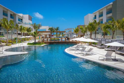 a swimming pool with chairs and umbrellas in a resort at Catalonia Grand Costa Mujeres All Suites & Spa - All Inclusive in Canc&uacute;n