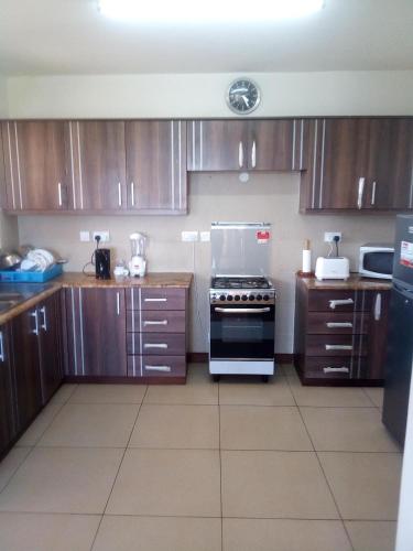 a kitchen with wooden cabinets and a stove at Shanzu Beach apartment with stunning Ocean view in Mwakirunge