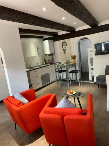 ein Wohnzimmer mit orangefarbenen Stühlen und eine Küche in der Unterkunft Ackerbürgerhaus von 1604 in Goslar