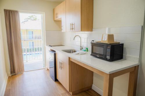a kitchen with a microwave and a sink with a window at Dunes Inn & Suites - Tybee Island in Tybee Island
