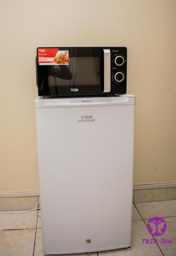 a microwave sitting on top of a white refrigerator at The Trio Inn in Nairobi