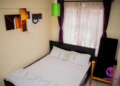 a small bedroom with a bed and a window at The Trio Inn in Nairobi