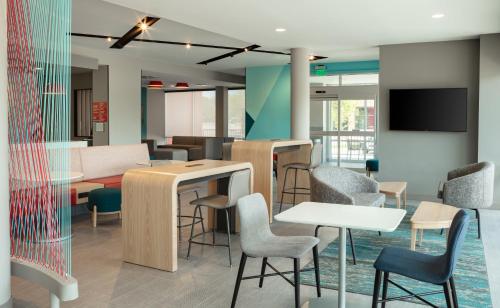 una sala d'attesa con tavoli, sedie e TV di avid hotels - Madison - Monona, an IHG Hotel a Monona