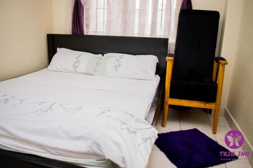 a bedroom with a bed and a chair at The Trio Inn in Nairobi