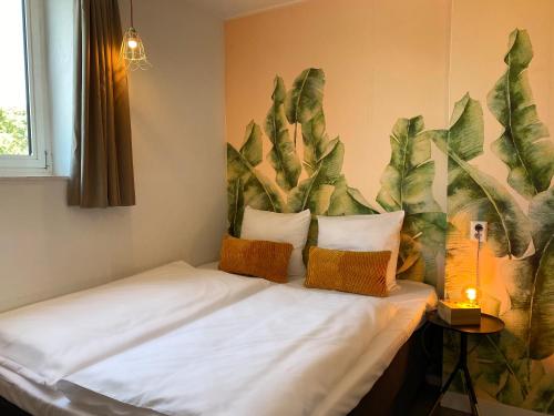 a bed in a room with a plant mural on the wall at Hotel Credible in Nijmegen