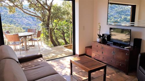 a living room with a couch and a tv and a balcony at A ALTEZZA Palombaggia in Porto-Vecchio