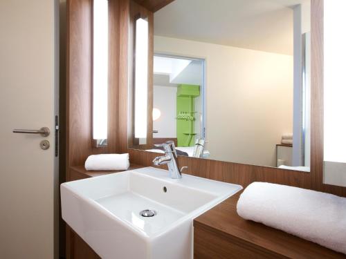 La salle de bains est pourvue d'un lavabo blanc et d'un miroir. dans l'établissement Campanile Saint-Etienne Est- Saint-Chamond, à Saint-Chamond