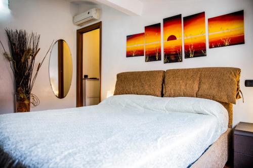 a bedroom with a white bed with two paintings on the wall at STUPENDA MANSARDA CENTRALISSIMA, finiture di lusso in Carrara