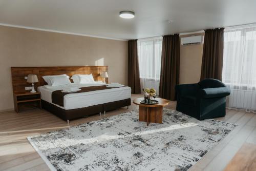 a bedroom with a bed and a chair and a rug at Aral Hotel in Aralʼsk