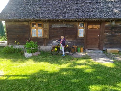 a boy standing next to a bike in front of a house at Kaszubska Zagroda in Lipuska Huta