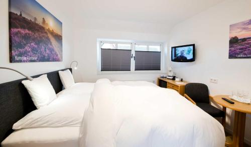 a bedroom with a white bed and a table at Landhaus Amelinghausen Ferienzimmer in Amelinghausen