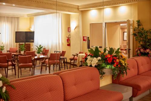 a waiting room with tables and chairs and a tv at Hotel Plaza in Tabiano
