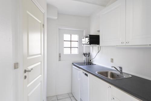 eine Küche mit weißen Schränken, einem Waschbecken und einem Fenster in der Unterkunft aday - Apartment suite 1 Aalborg Center in Aalborg