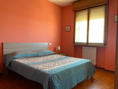 a bedroom with a bed with orange walls and a window at Da Debbydue in Pisa