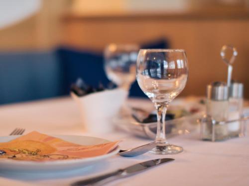 a table with two wine glasses and a plate on it at Hotel Neckarblick in Bad Wimpfen