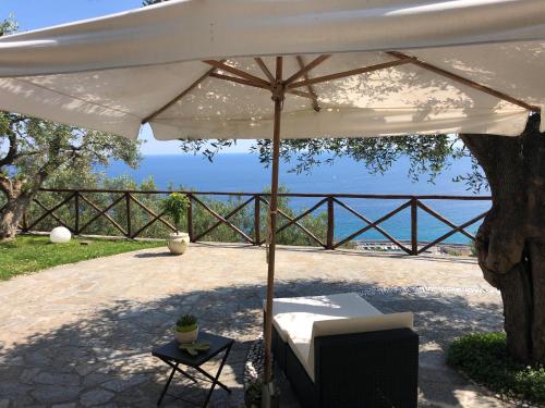 a white umbrella on a patio with the ocean in the background at Villa Degli Ulivi B&B in Finale Ligure