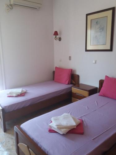 two beds in a room with pink pillows at Eirini in Neochórion
