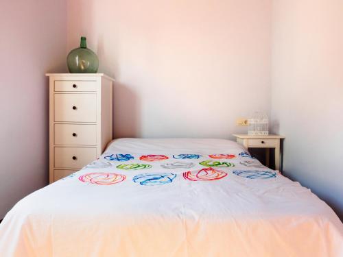 uma cama com uma colcha branca com anéis coloridos em Casa de playa TABI Caión- A Coruña (VUT-CO-000899) em Cayón
