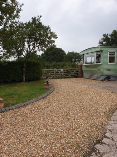 a green caravan parked next to a gravel driveway at Ruth's Rest Country Retreat with private Hot Tub in Shrewsbury