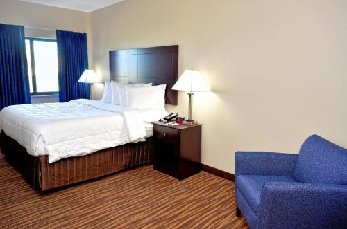 Habitación de hotel con cama y silla azul en Cobblestone Inn & Suites - Monticello, en Monticello