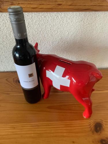 a bottle of wine next to a red cow figurine at Studios Bellevue 1 et 2, ski lift 150m in Veysonnaz