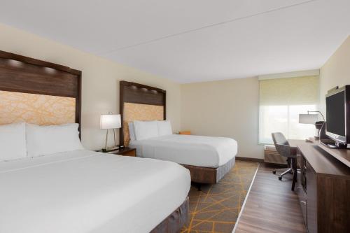 a hotel room with two beds and a flat screen tv at Holiday Inn La Mirada Buena Park by IHG in La Mirada