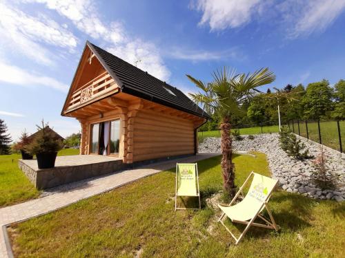 Cabaña de madera pequeña con 2 sillas en el césped en Wioska Jasia i Małgosi en Izdebnik