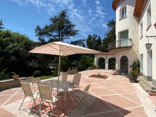 een tafel en stoelen met een parasol op een patio bij Espectacular Casa Chateau en el centro de Olot in Olot
