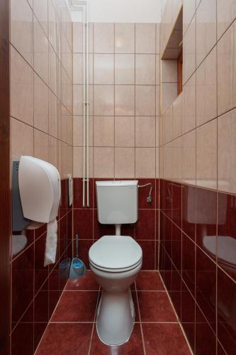 a bathroom with a toilet in a tiled room at Illés Hotel in Szeged