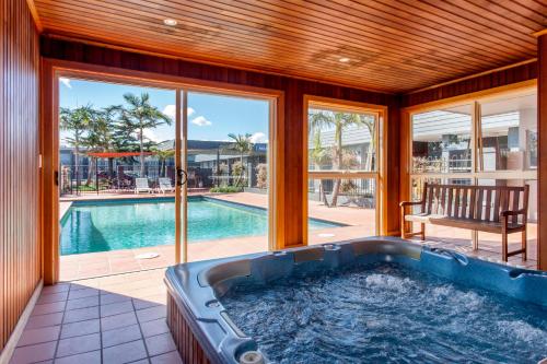 a jacuzzi tub in a house with a pool at Sunshine Motor Inn in Ardeer