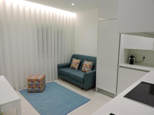 a living room with a blue couch and a stool at Apartamento Atalaia in Nazaré