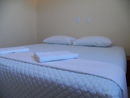 two beds in a room with white sheets and pillows at Hotel Prata Express in Pratânia